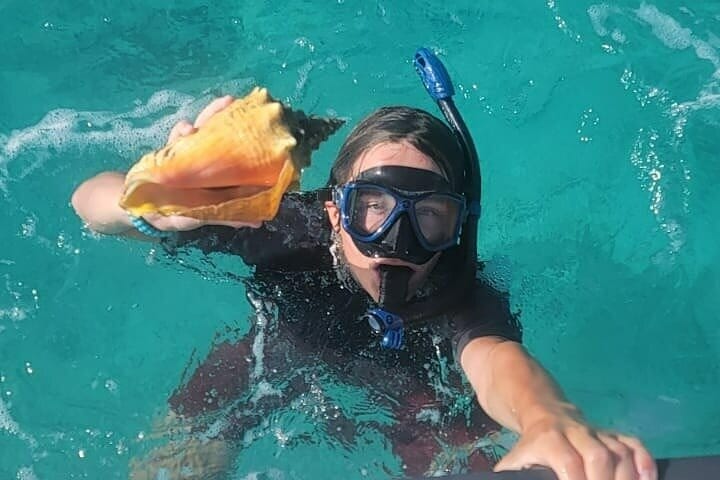 a person in a scuba mask holding a seashell