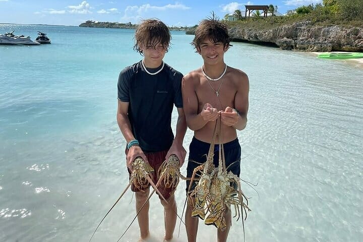 two boys holding lobsters in the water