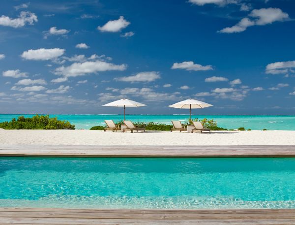 a pool with chairs and umbrellas on a beach