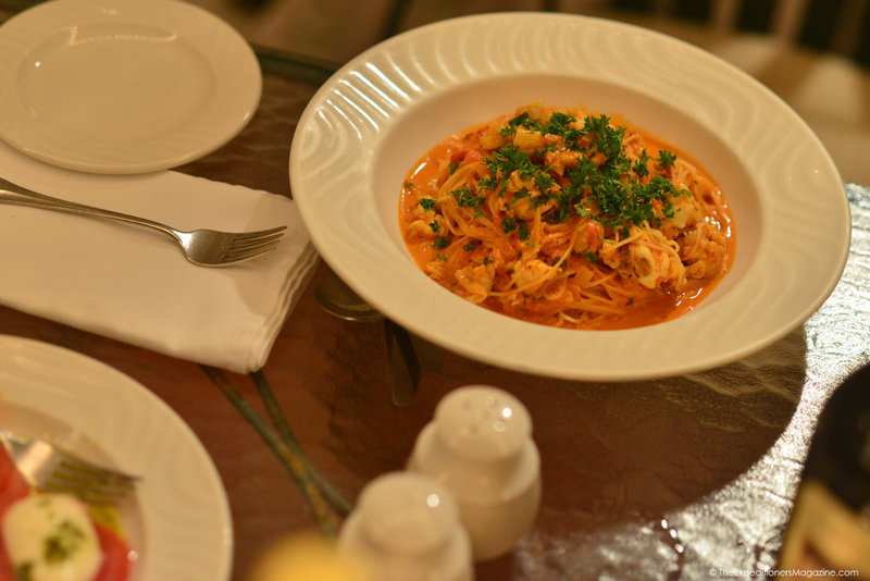 a bowl of pasta with shrimp and parsley on a table