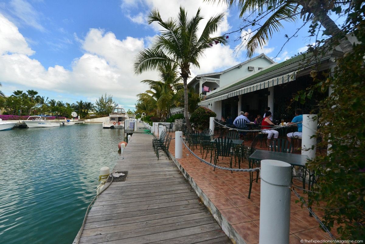 a group of people sitting at tables outside by a dock