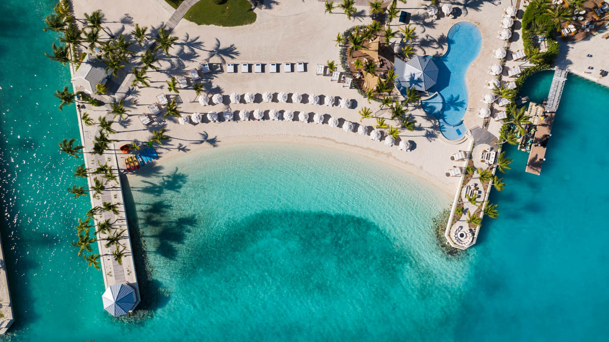 an aerial view of a beach with a pool and umbrellas