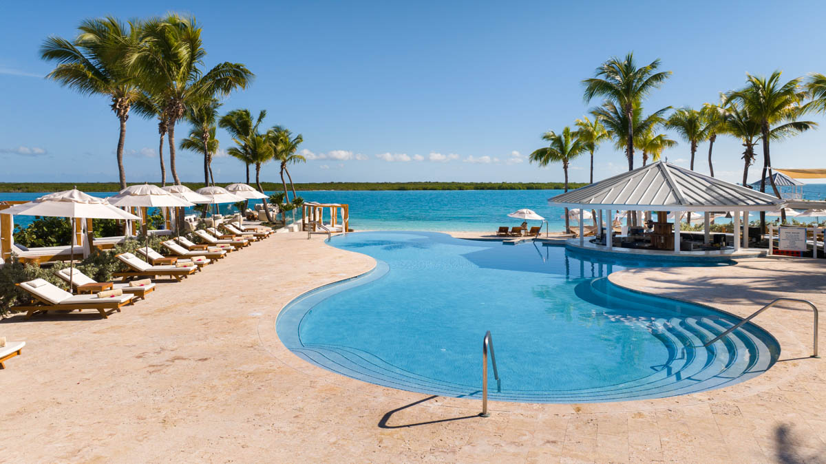 a pool with umbrellas and chairs by the water