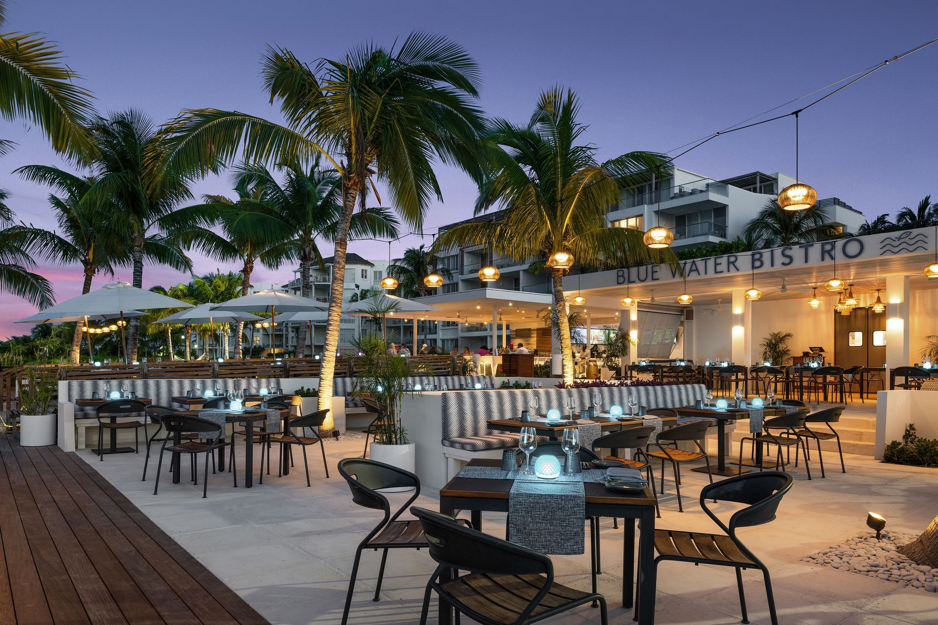 a restaurant with tables and chairs and palm trees