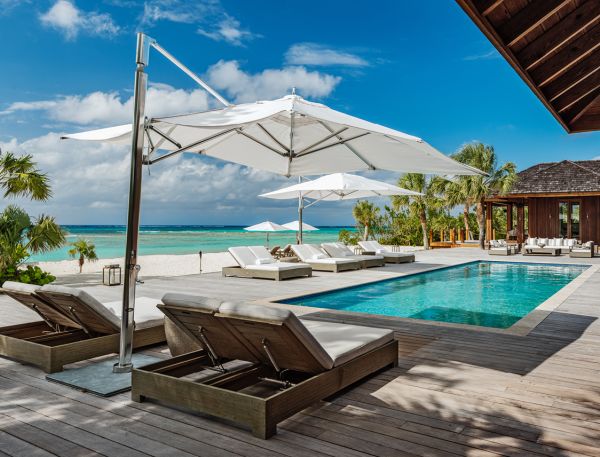 a pool with lounge chairs and umbrellas on a beach