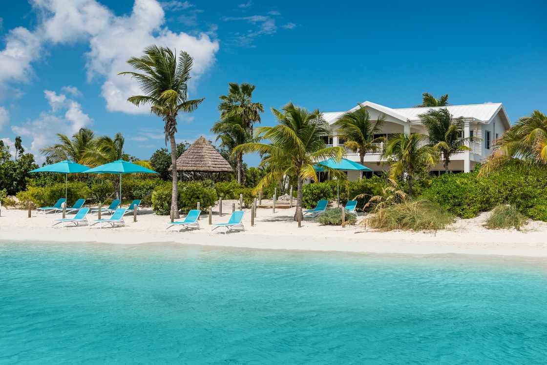 a beach with chairs and umbrellas and a building