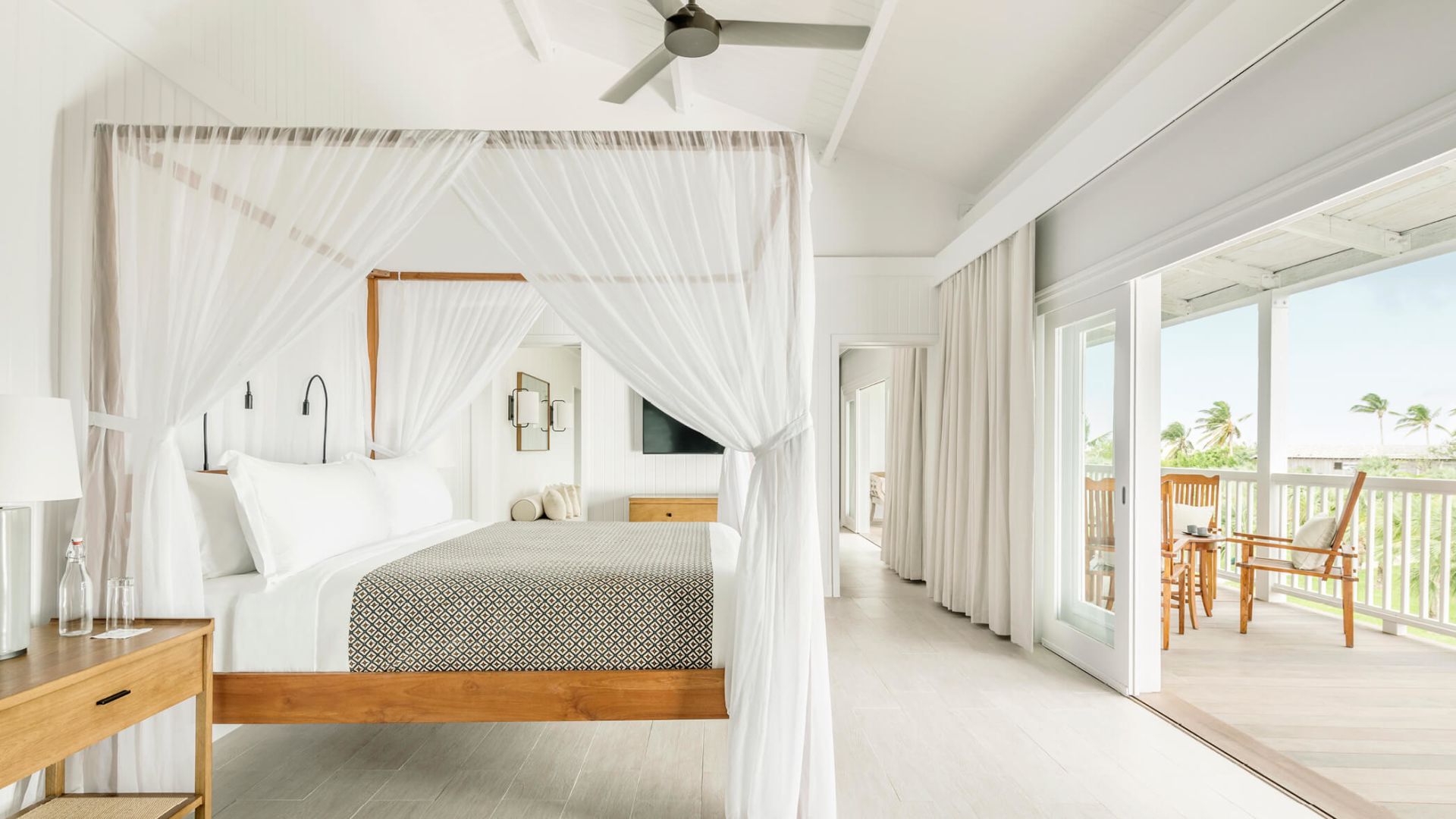 a white bedroom with a canopy bed and a ceiling fan