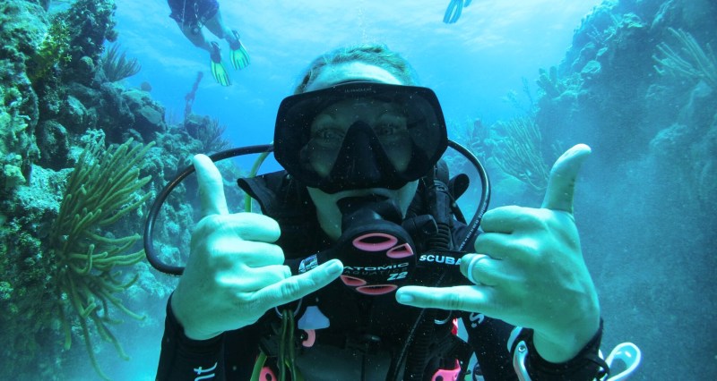 a woman in scuba gear making hand gestures