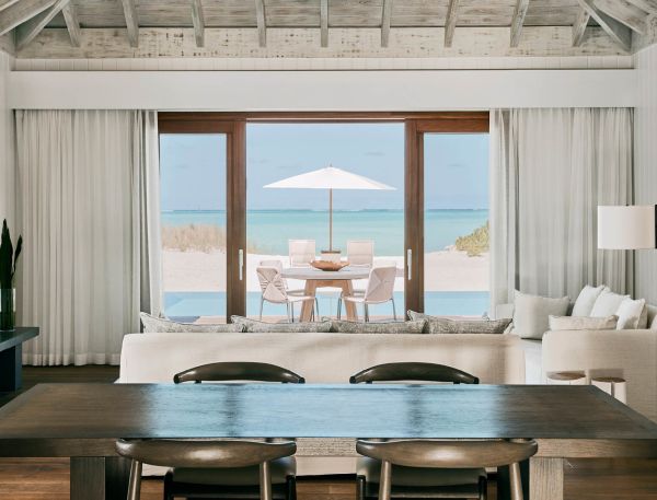 a room with a table and chairs and a table with a beach view