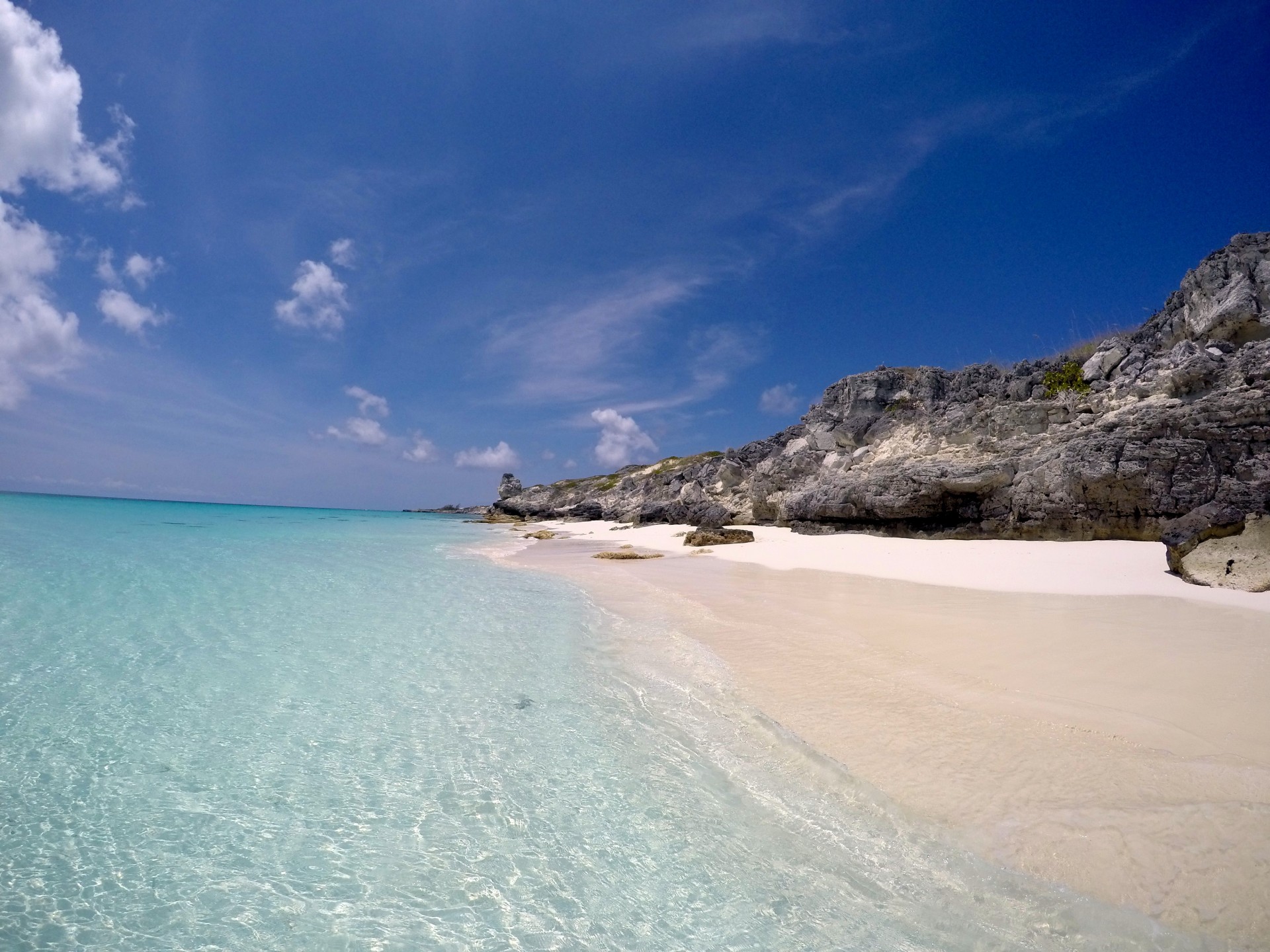 a beach with clear blue water and rocks