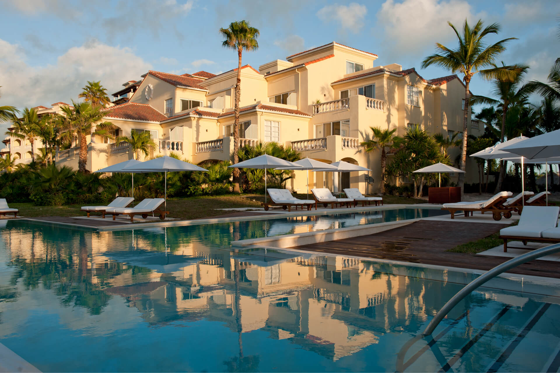 a pool with lounge chairs and umbrellas in front of a building