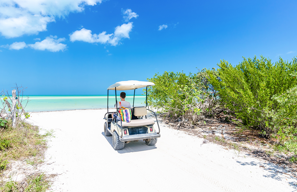 a man driving a golf cart on a beach