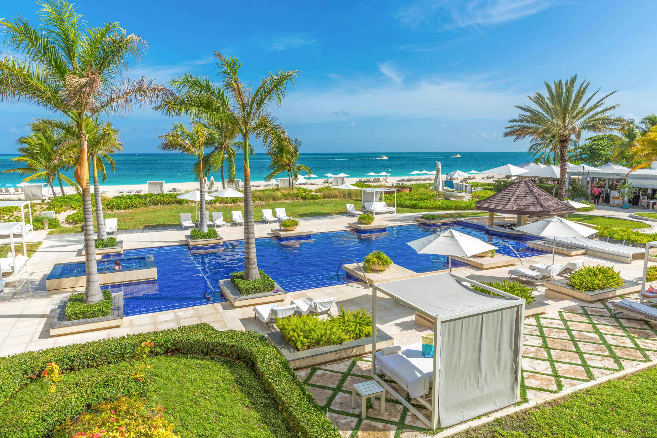 a pool with lounge chairs and palm trees on a beach