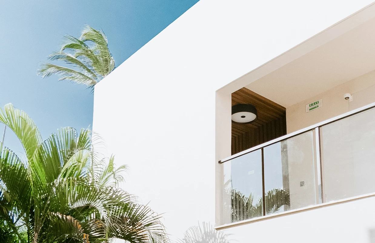 a balcony with a glass railing and palm trees