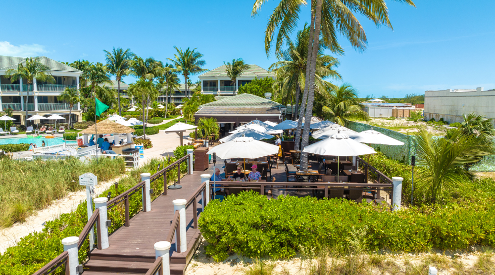 a group of people sitting at tables and umbrellas on a beach