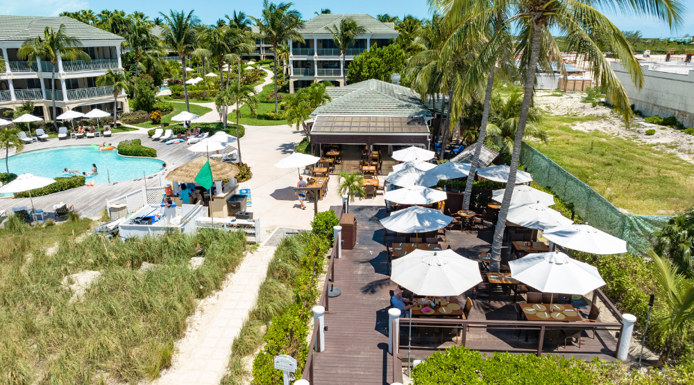 a group of people sitting at tables and chairs outside of a resort