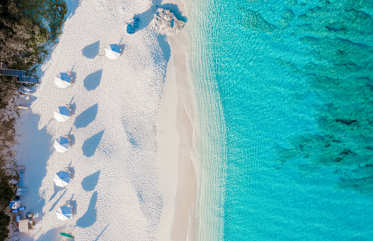 an aerial view of a beach with umbrellas and water