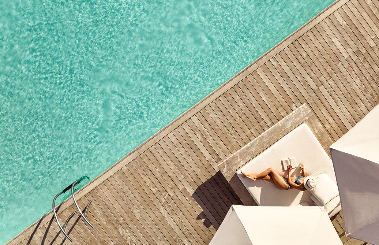 a woman lying on a deck near a pool