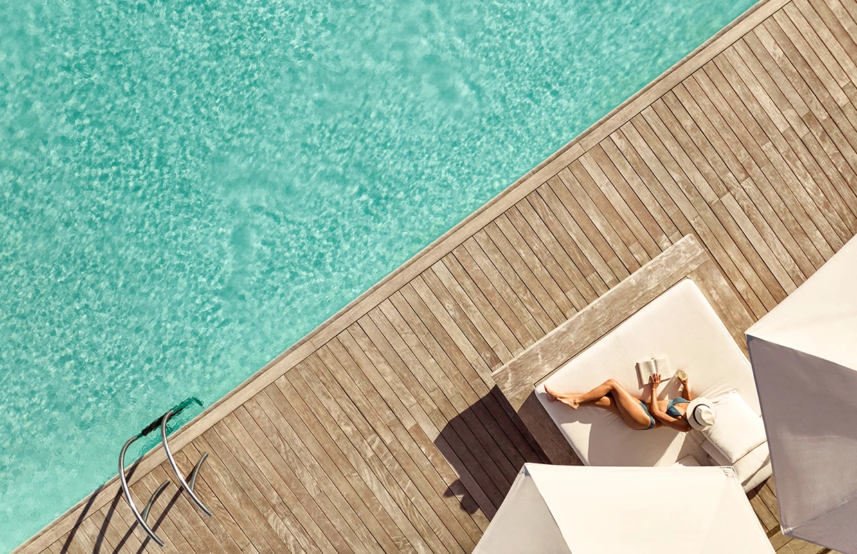 a woman lying on a deck near a pool