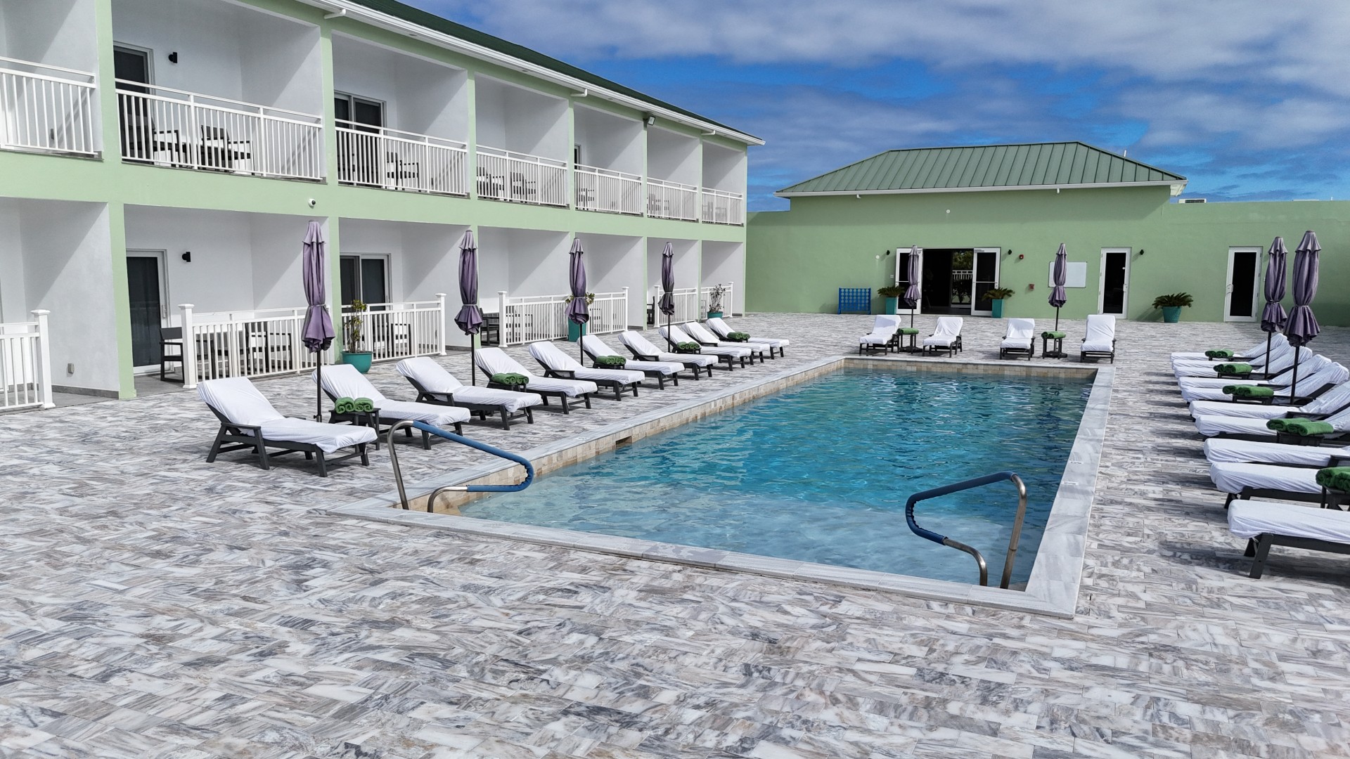 a pool with lounge chairs and umbrellas in front of a building