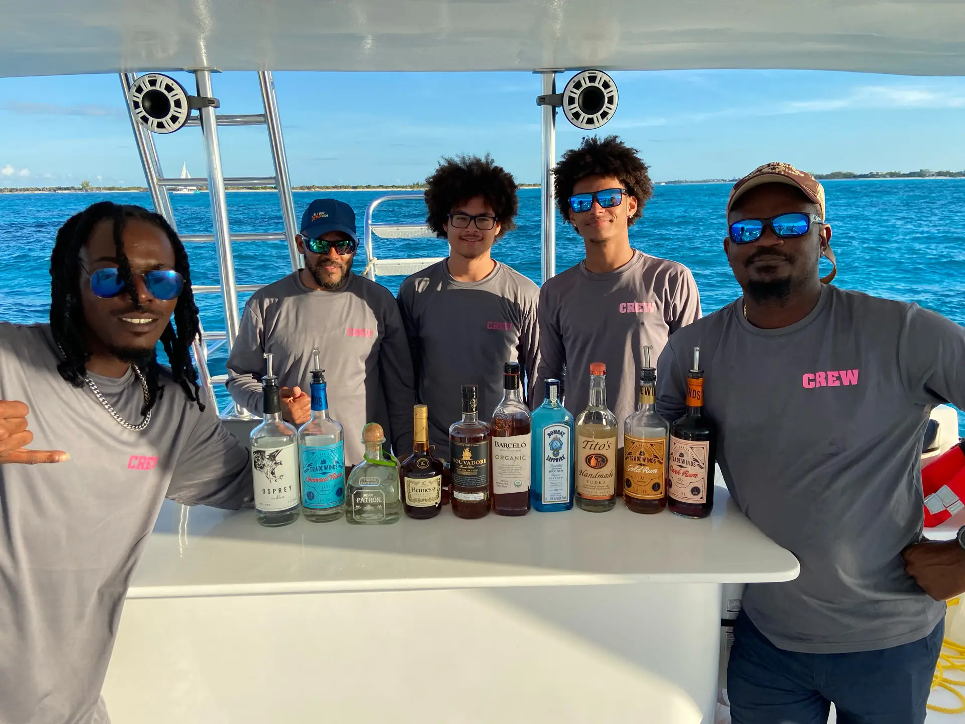 a group of men standing behind a table with bottles of alcohol