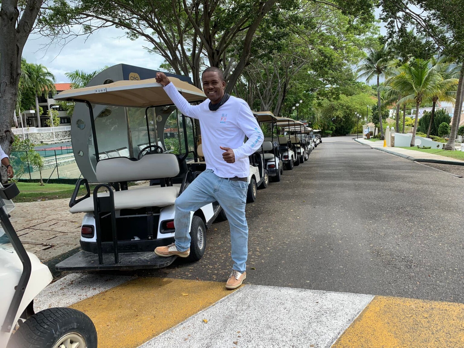 a man standing on the side of a road with a golf cart