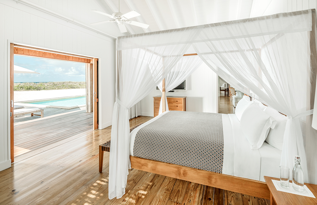 a white canopy bed in a room with a pool in the background