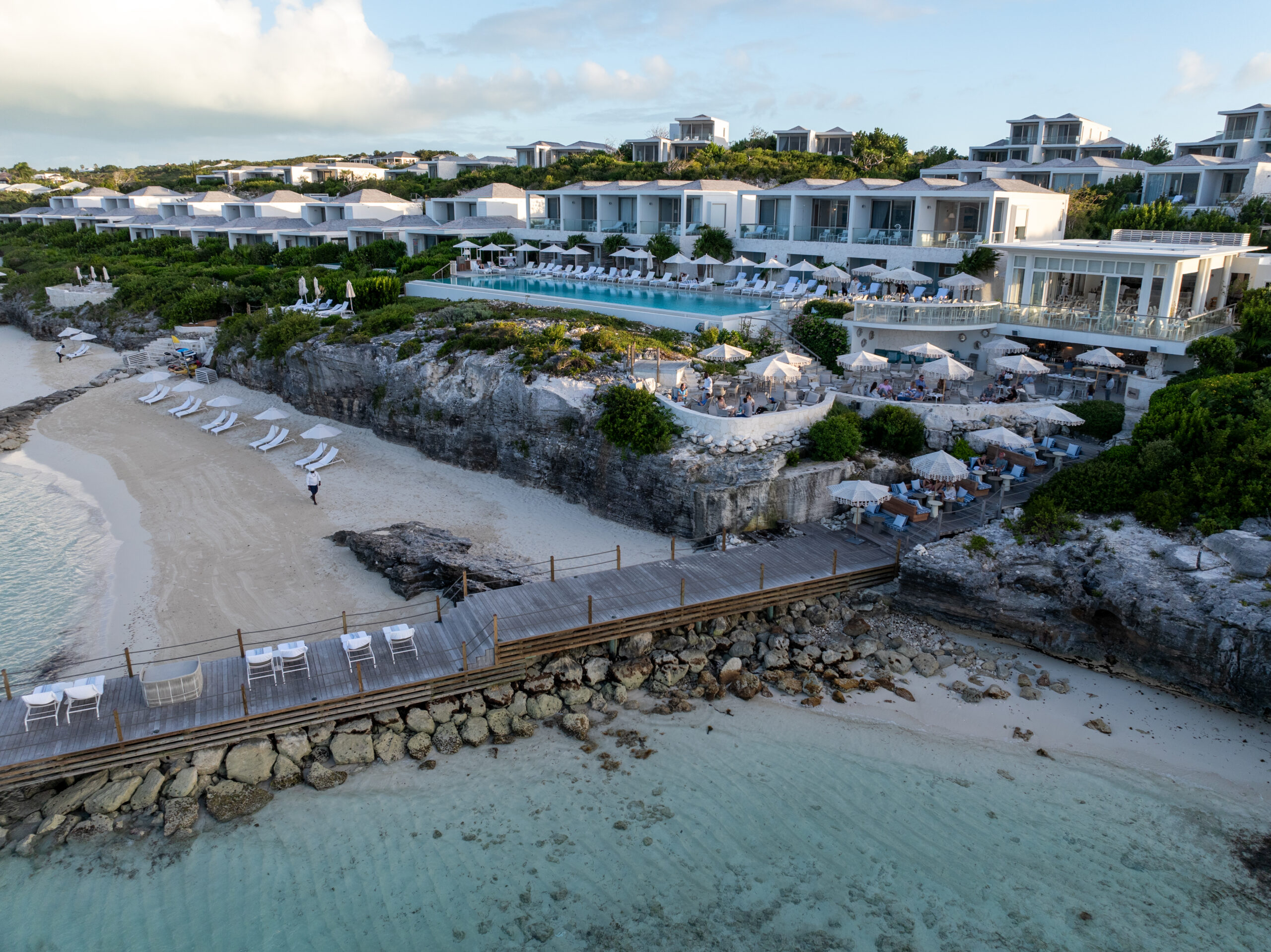a beach with white buildings and a wooden bridge