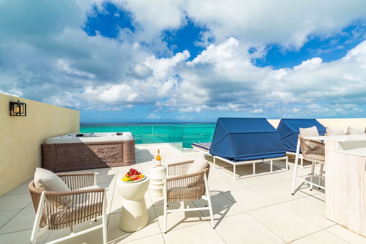 a patio with chairs and a hot tub overlooking the ocean