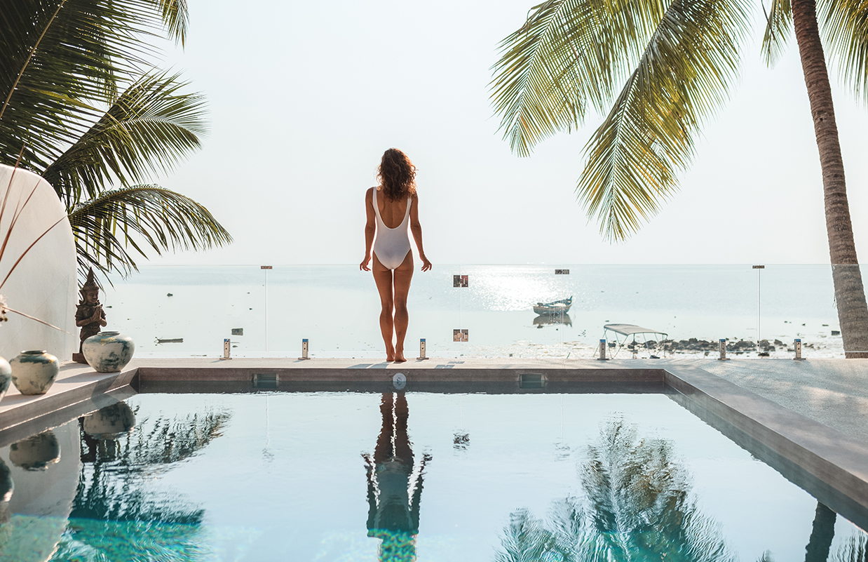 a woman in a white swimsuit standing by a pool