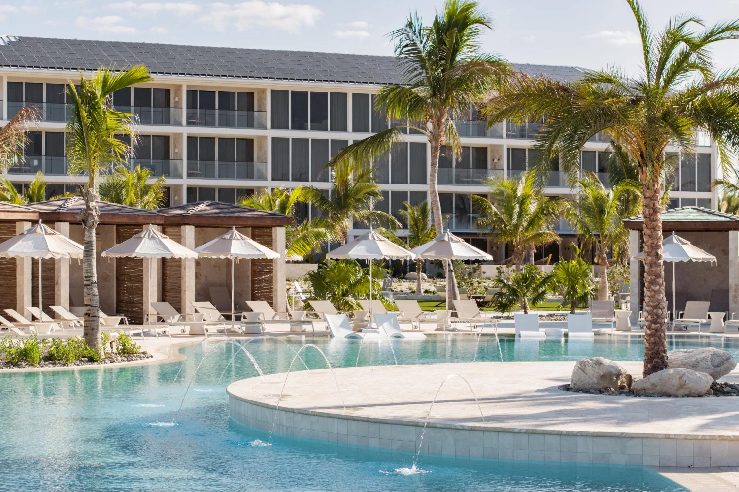 a pool with umbrellas and chairs in front of a building