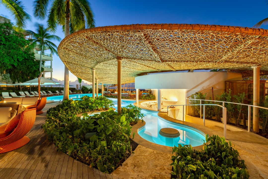 a pool with a large umbrella and palm trees