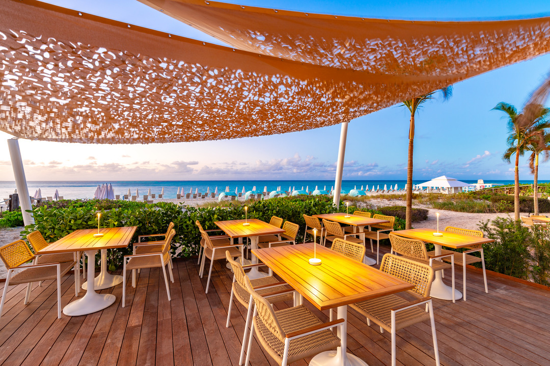 a restaurant with tables and chairs on a deck by the beach