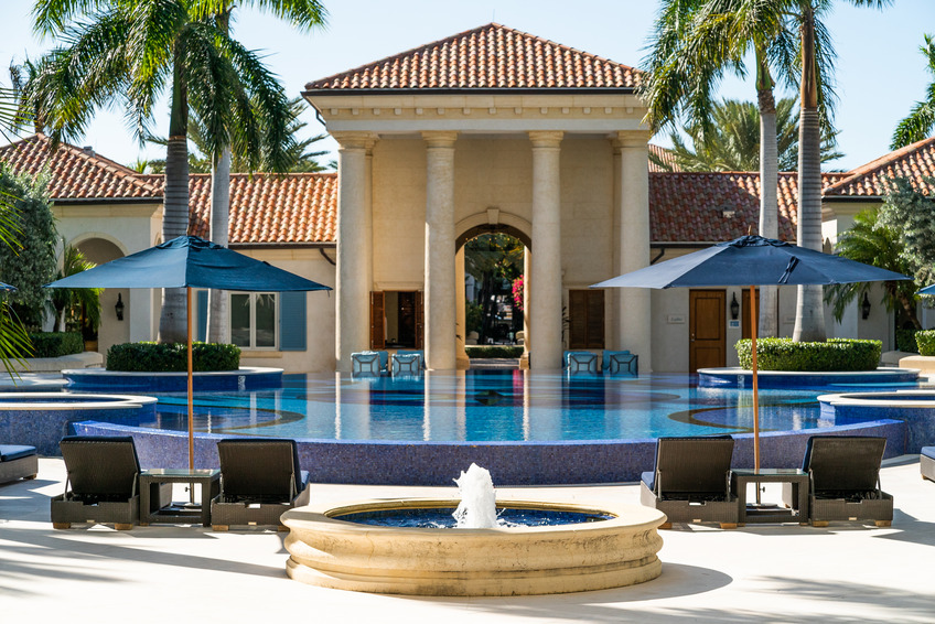 a pool with umbrellas and chairs in front of a building