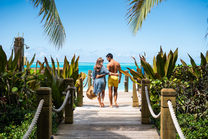 a man and woman on a wooden bridge with rope and plants