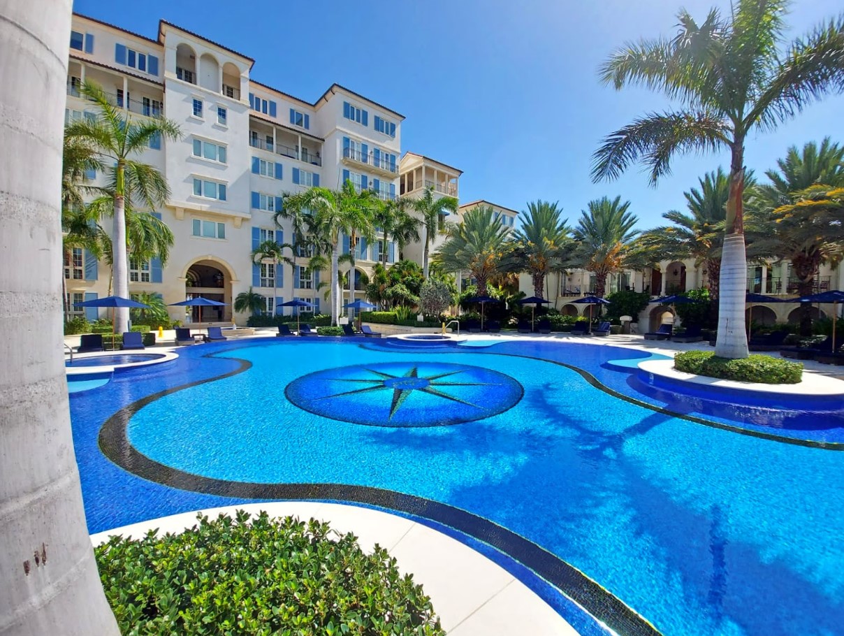 a pool with palm trees and a building