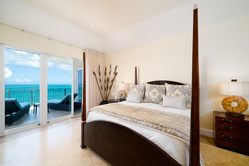 a bed with a glass door leading to a balcony