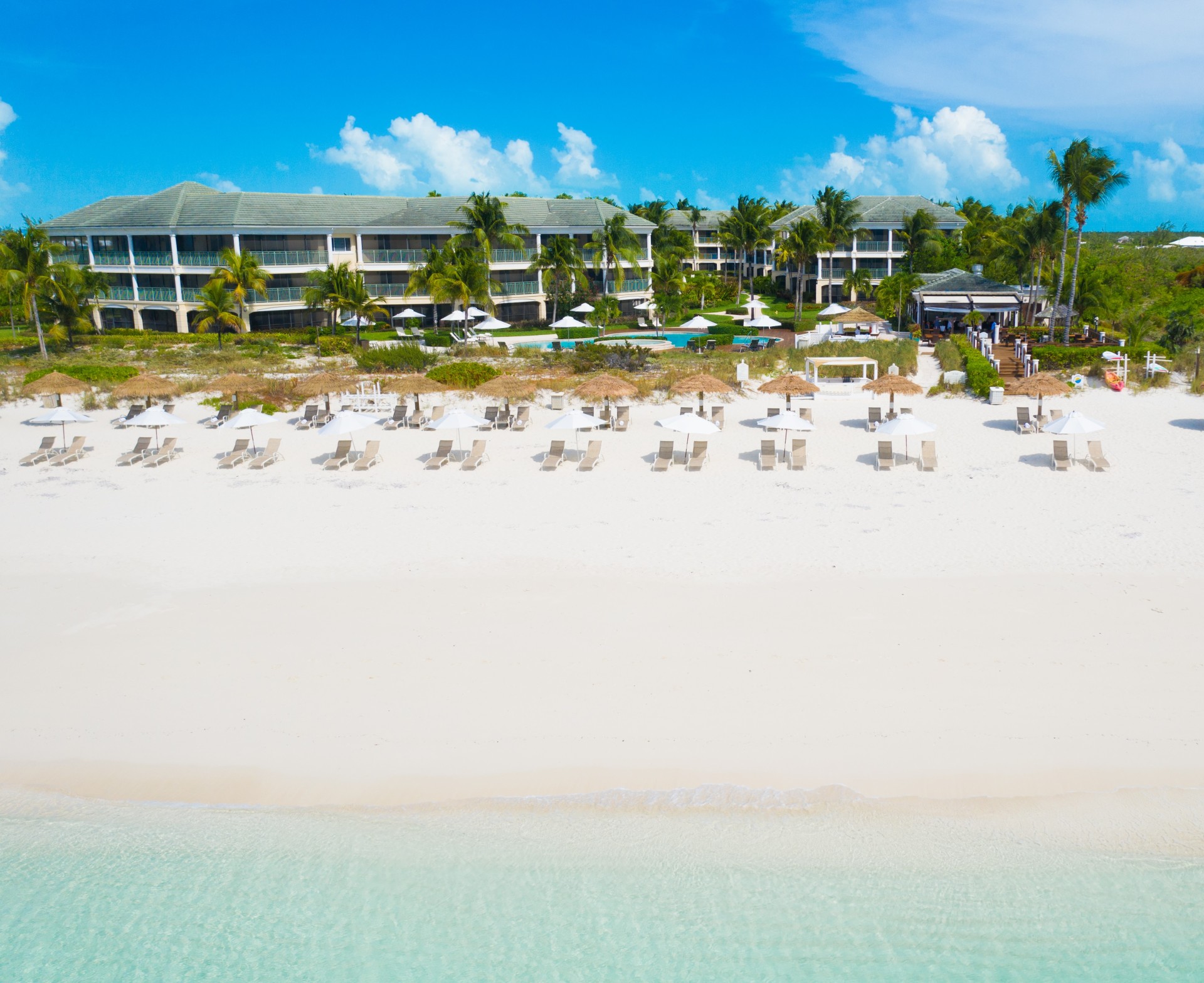 a beach with chairs and umbrellas and a building in the background