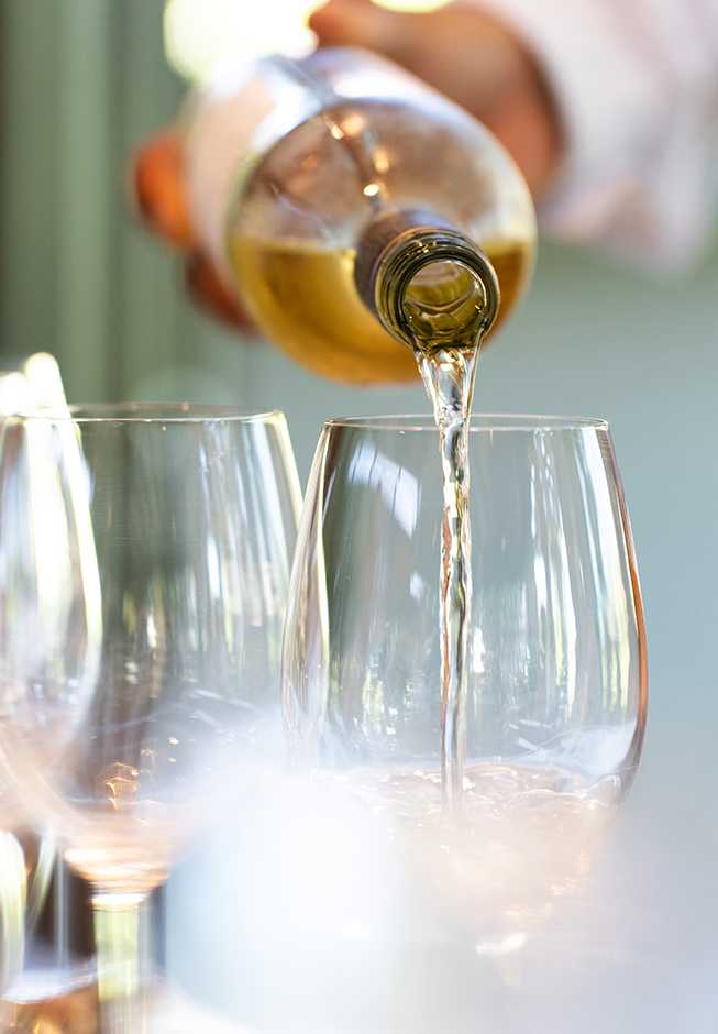 a person pouring wine into a glass