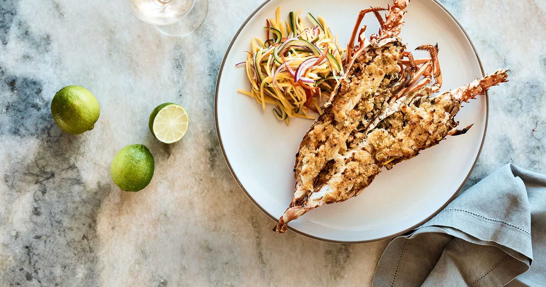 a lobster on a plate with noodles and limes