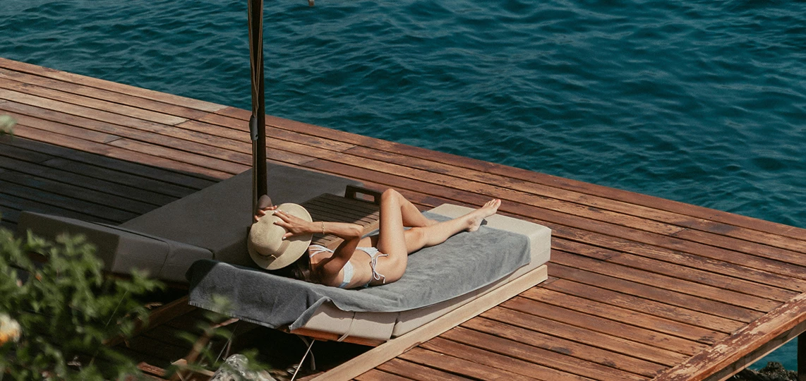 a woman in a garment lying on a deck by the water