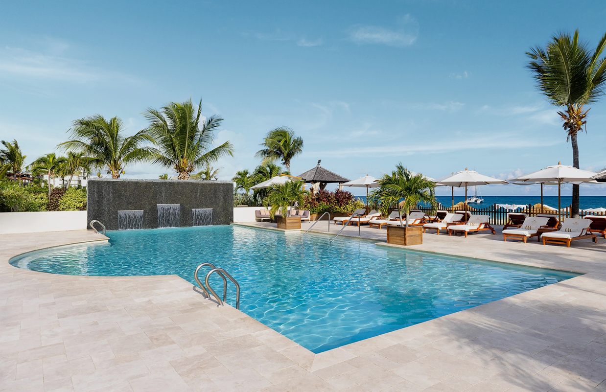 a swimming pool with a waterfall and palm trees