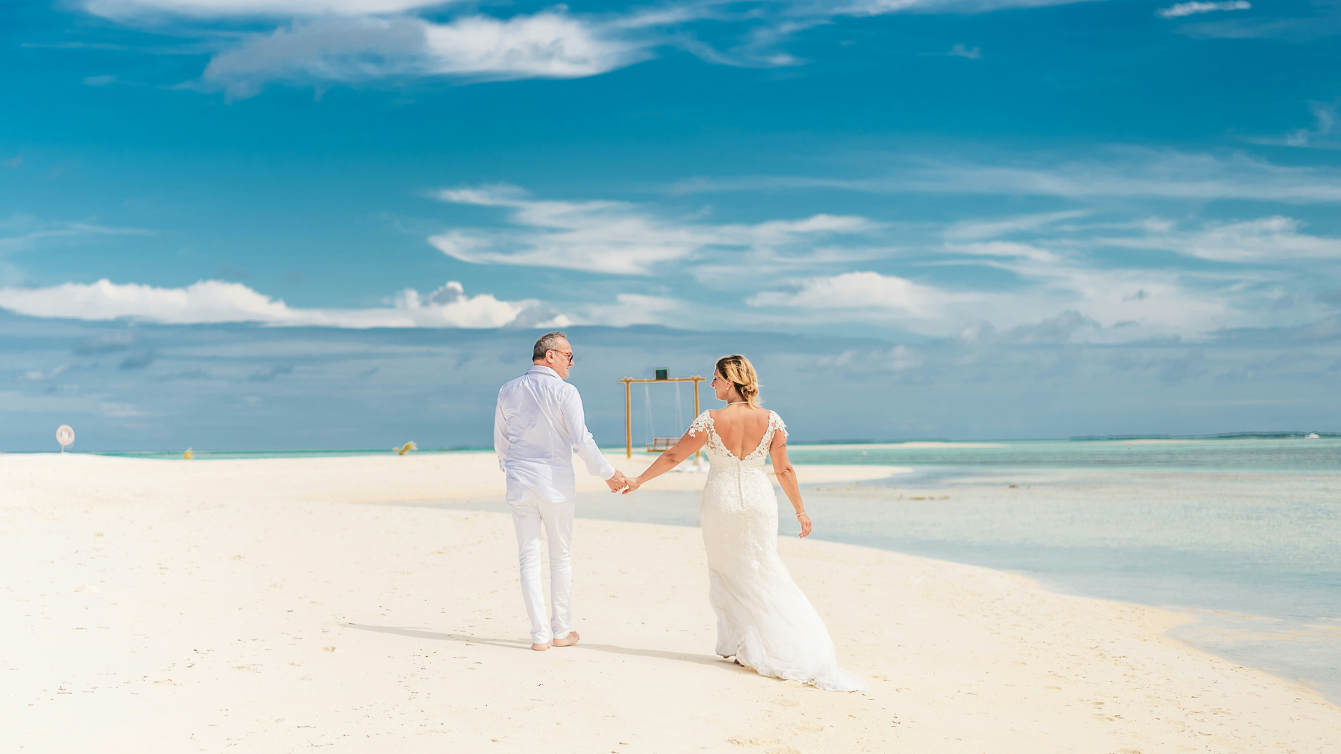 a man and woman holding hands on a beach