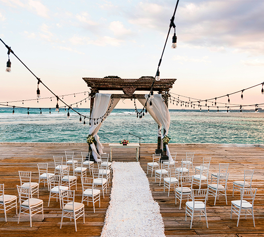 a wedding ceremony set up on a dock with chairs and a long white carpet