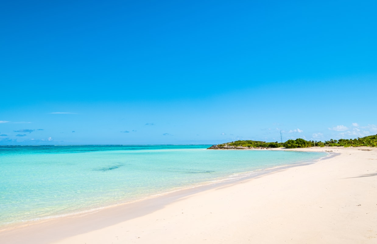 a beach with clear blue water and a small island