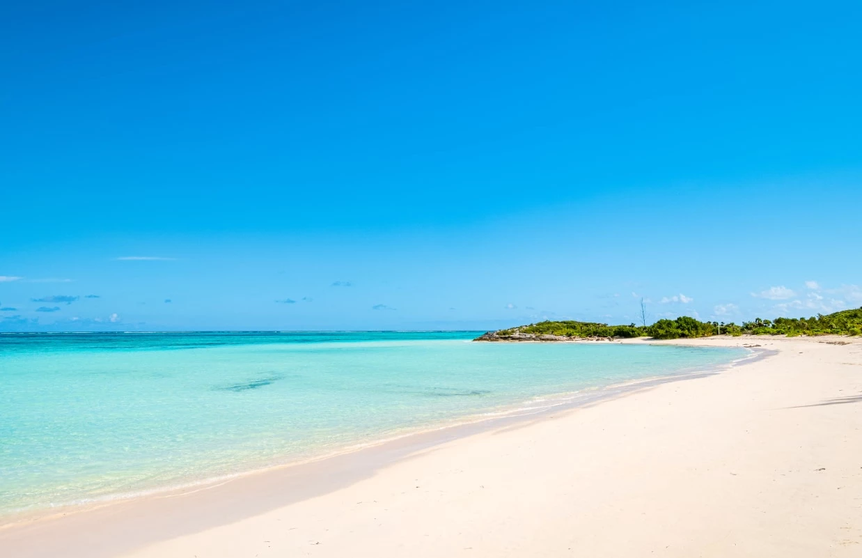 a beach with clear blue water and a small island