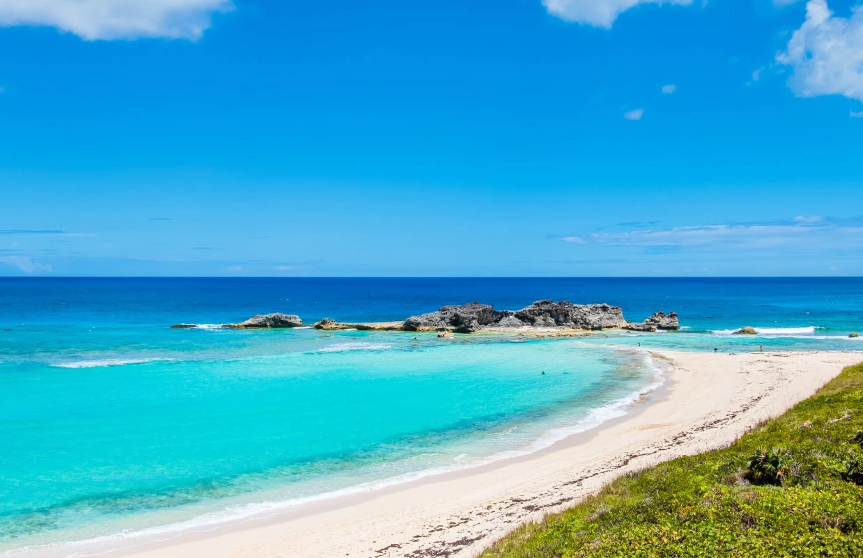a beach with blue water and rocks