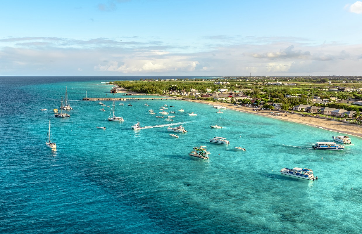 boats in a body of water with boats and a beach and land