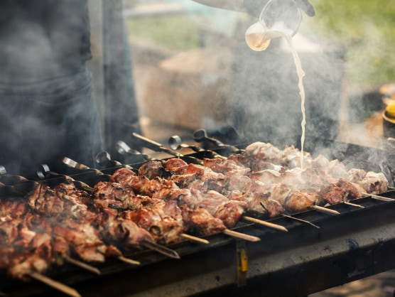 a person pouring liquid on a barbecue