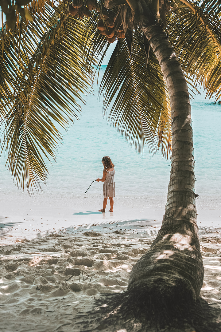 a woman standing on a beach with a stick